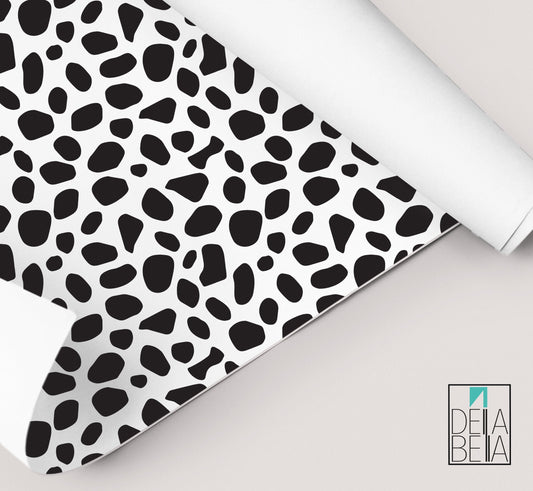 A rolled up piece of vinyl wrap with a dalmatian black spots pattern, partially unrolled to show the self-adhesive side.