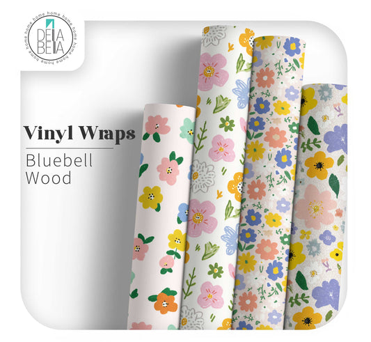 Della Bella UK British Meadow Collection mockup featuring four vertical rolls of matte peel-and-stick vinyl furniture wrap. The rolls showcase a variety of hand-painted floral patterns in pastel pink, vibrant blue, and mustard yellow, designed for home upcycling and maximalist DIY decor.