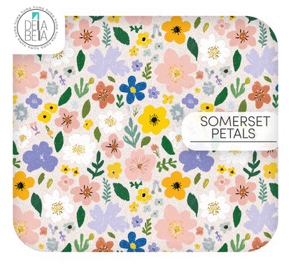 A maximalist, painterly floral vinyl wrap for furniture and kitchens. Features large, expressive blooms in lavender purple, rosy pink, and sunshine yellow with rich green foliage on a textured off-white background.