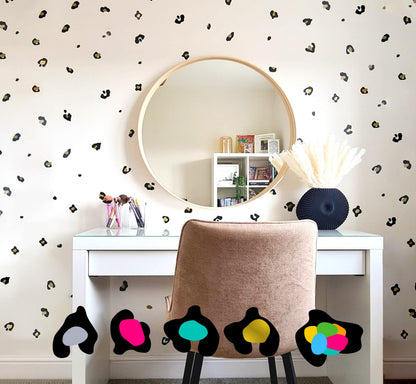 A room with walls decorated with leopard print dot stickers, featuring a vanity, chair, and large circular mirror.