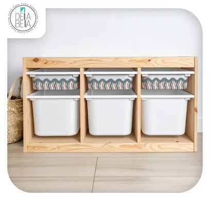 A light natural trofast  storage organizer with three open compartments holding white plastic bins, shown against a white wall and light wood floor. A woven basket is partially visible on the left, and a Dela Benta logo appears in the top-left corner.