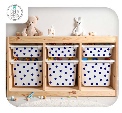 A light natural wood storage cabinet with six white plastic bins decorated with blue polka dots, styled with toys and plush toys on top against a white wall.