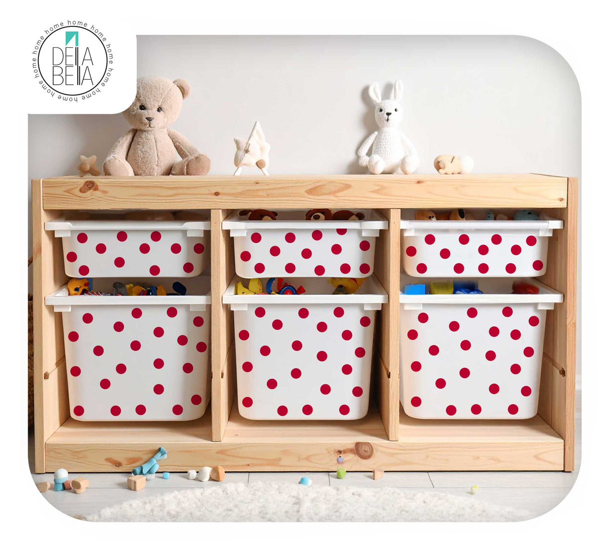 A light natural wood children's storage cabinet with six white plastic bins covered in red polka dots, styled with stuffed toys on top against a white wall.
