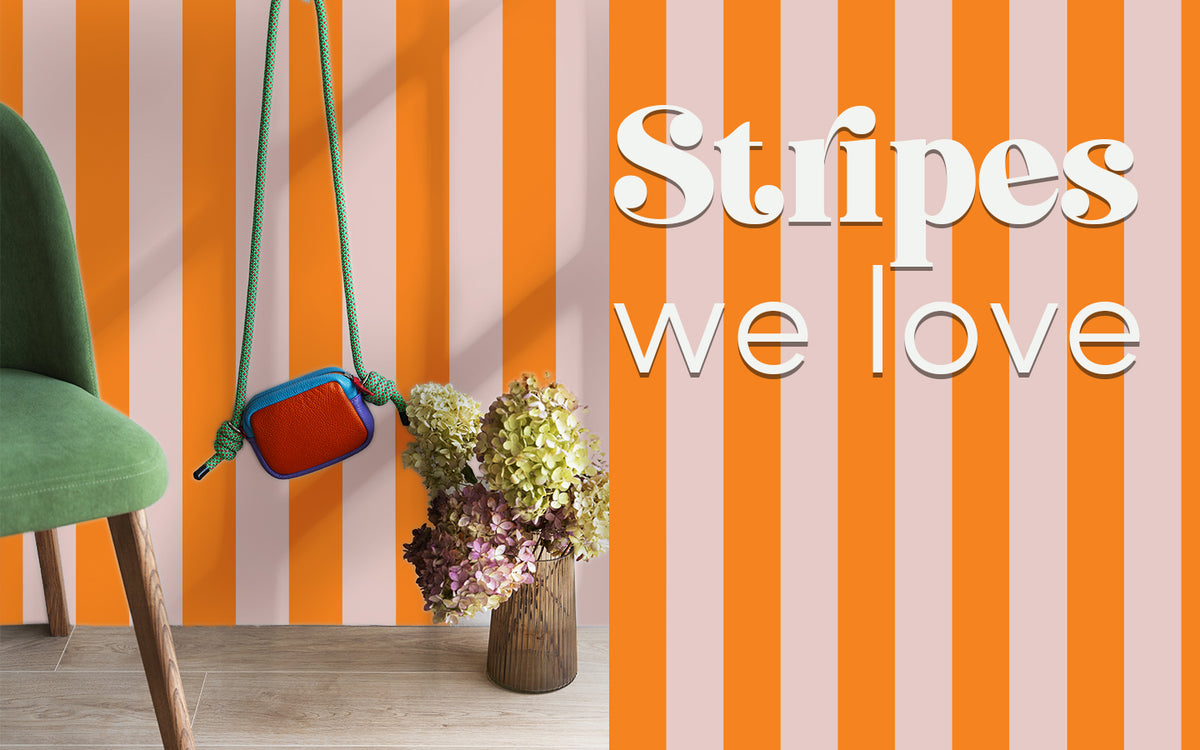 A stylish room with a pink and orange striped wall, showcasing the "Stripes We Love" furniture sticker collection.